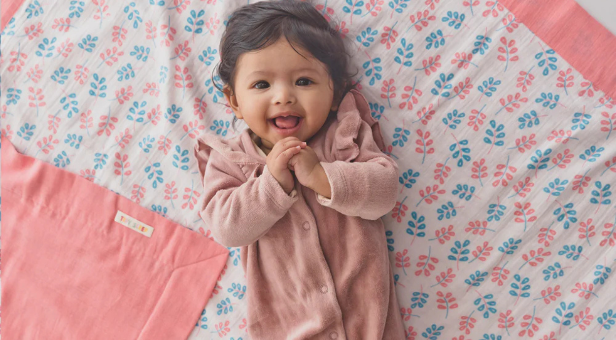 A baby lying on colorful dohar blanket