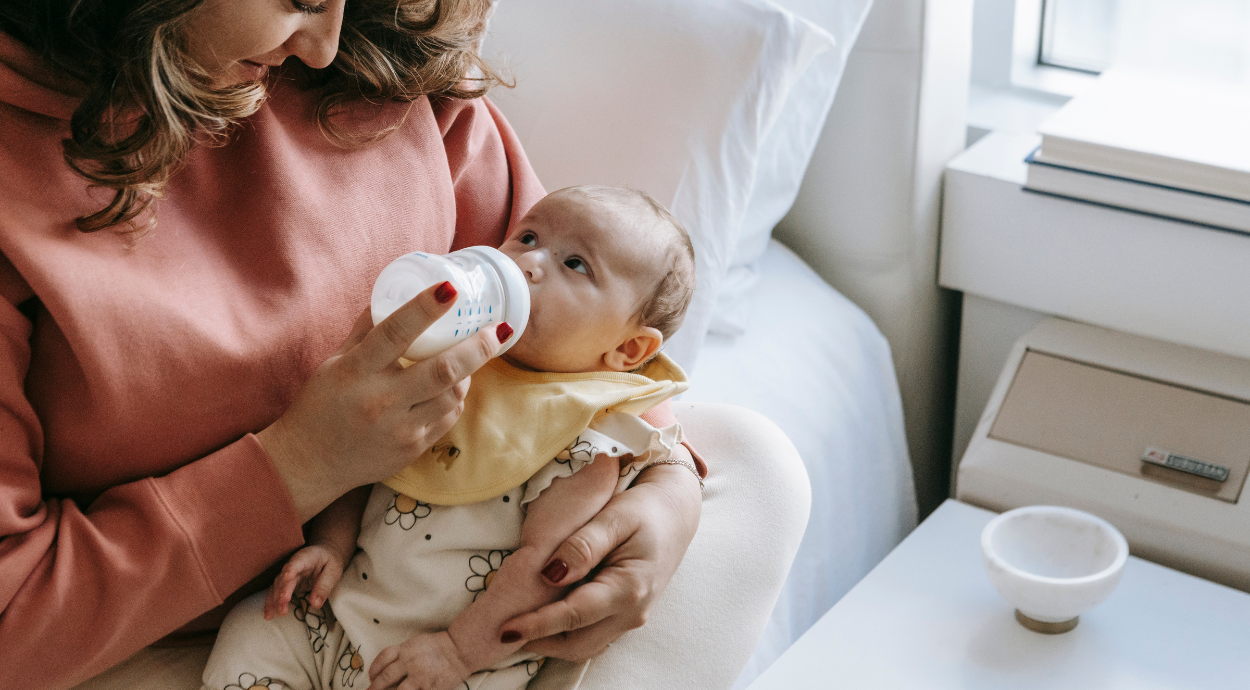 A mother holding her newborn baby and feeding her milk from bottle