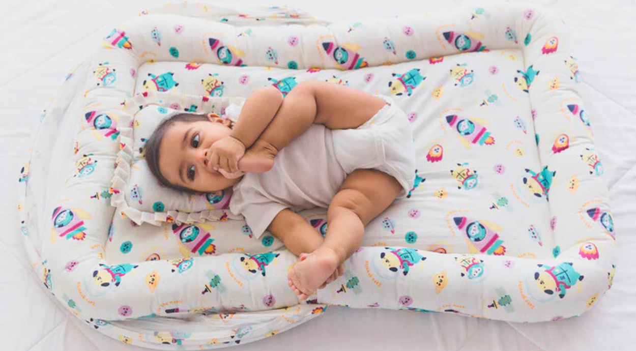 A baby lying in a baby bed gadda set which has space theme