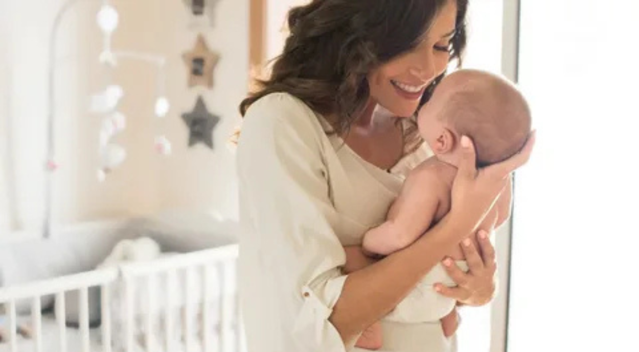 A mother lovingly cradles her baby, surrounded by soft natural light in a cozy nursery filled with calming decor.