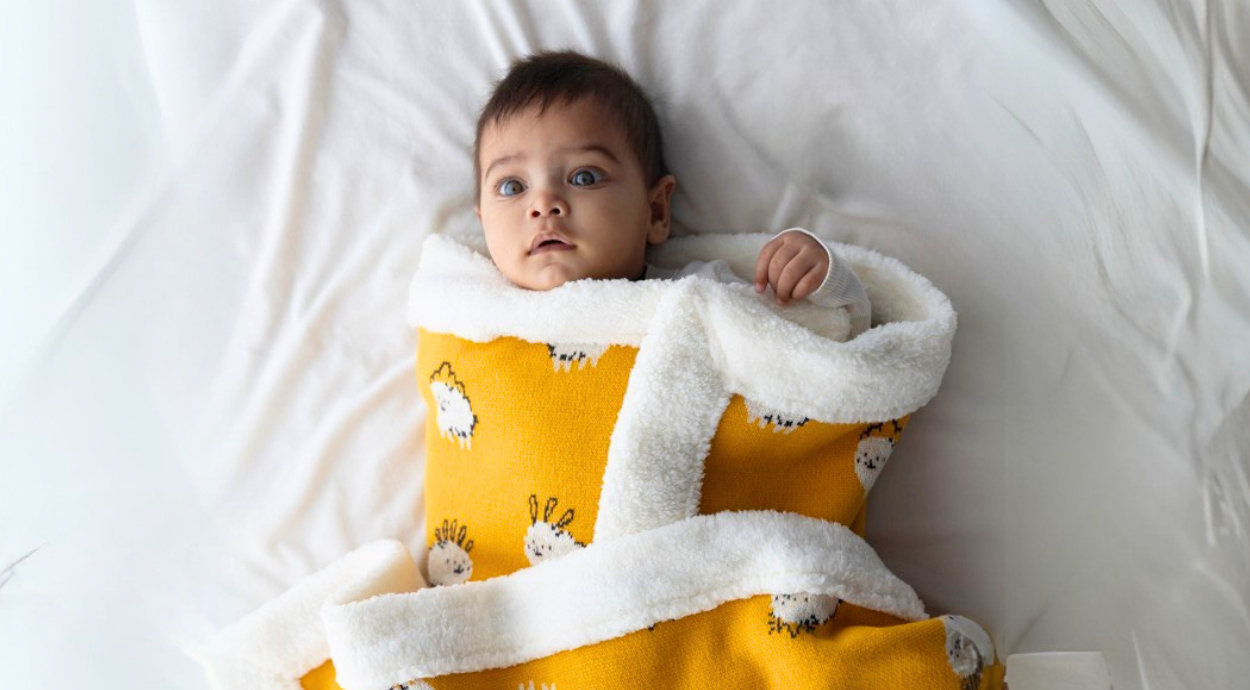 A baby wrap in a yellow fleece blanket
