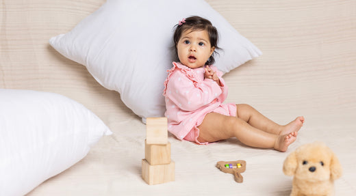 A cute baby sitting on bed and playing with toys