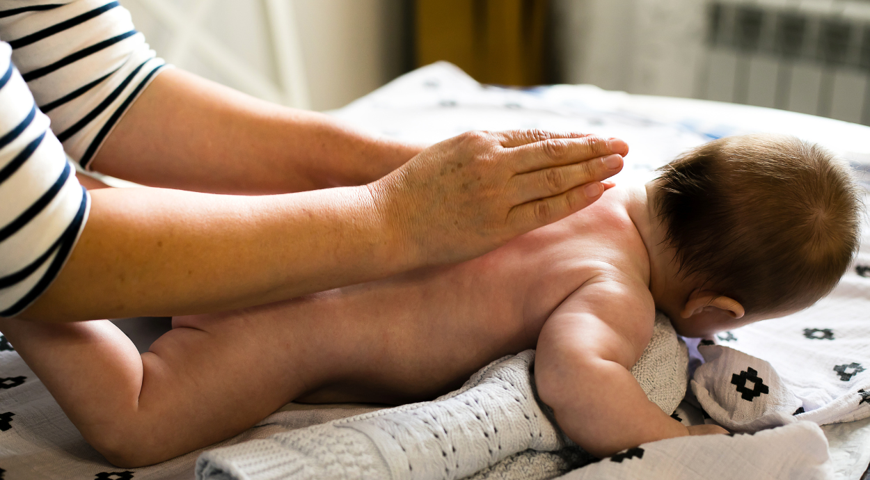 A lady doing oil massage of a newborn baby