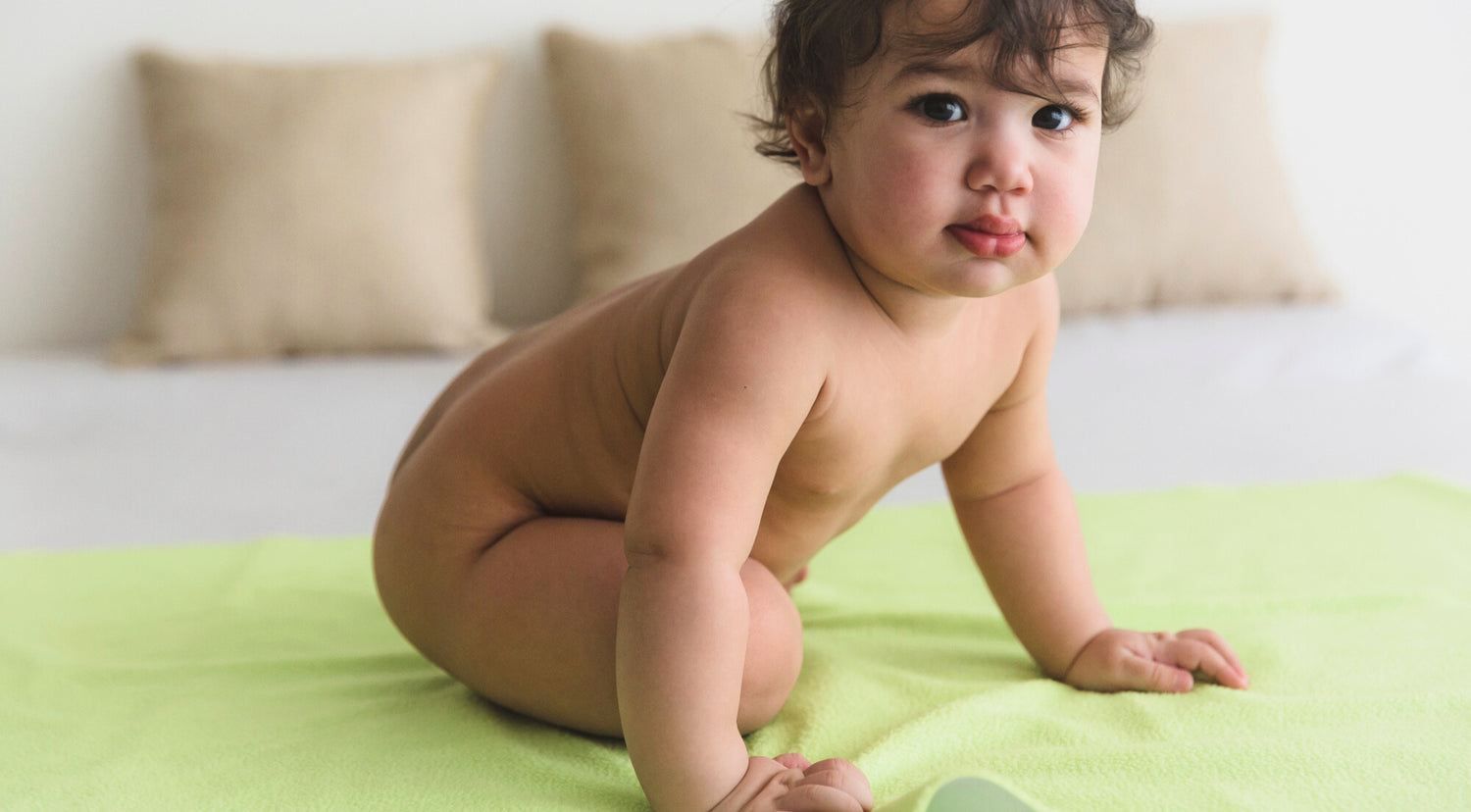 A cute baby sitting on the dry sheets