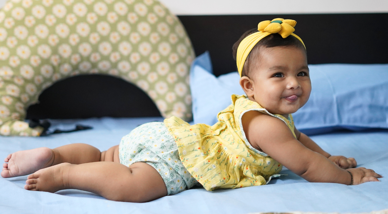 A baby girl in yellow color cord set lying in a bed