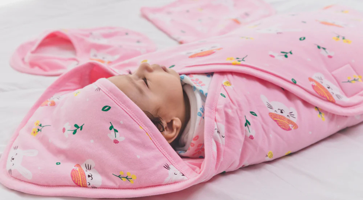 A baby wrapped in a pink colorful print hodded wrapper blanket