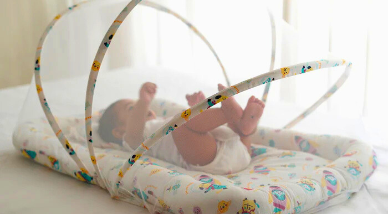 A baby lying in a space printed gadda set with mosquito net