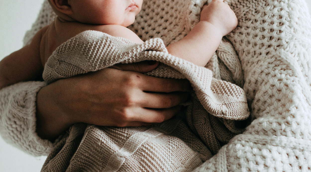 A mother hugged newborn baby in a shawl