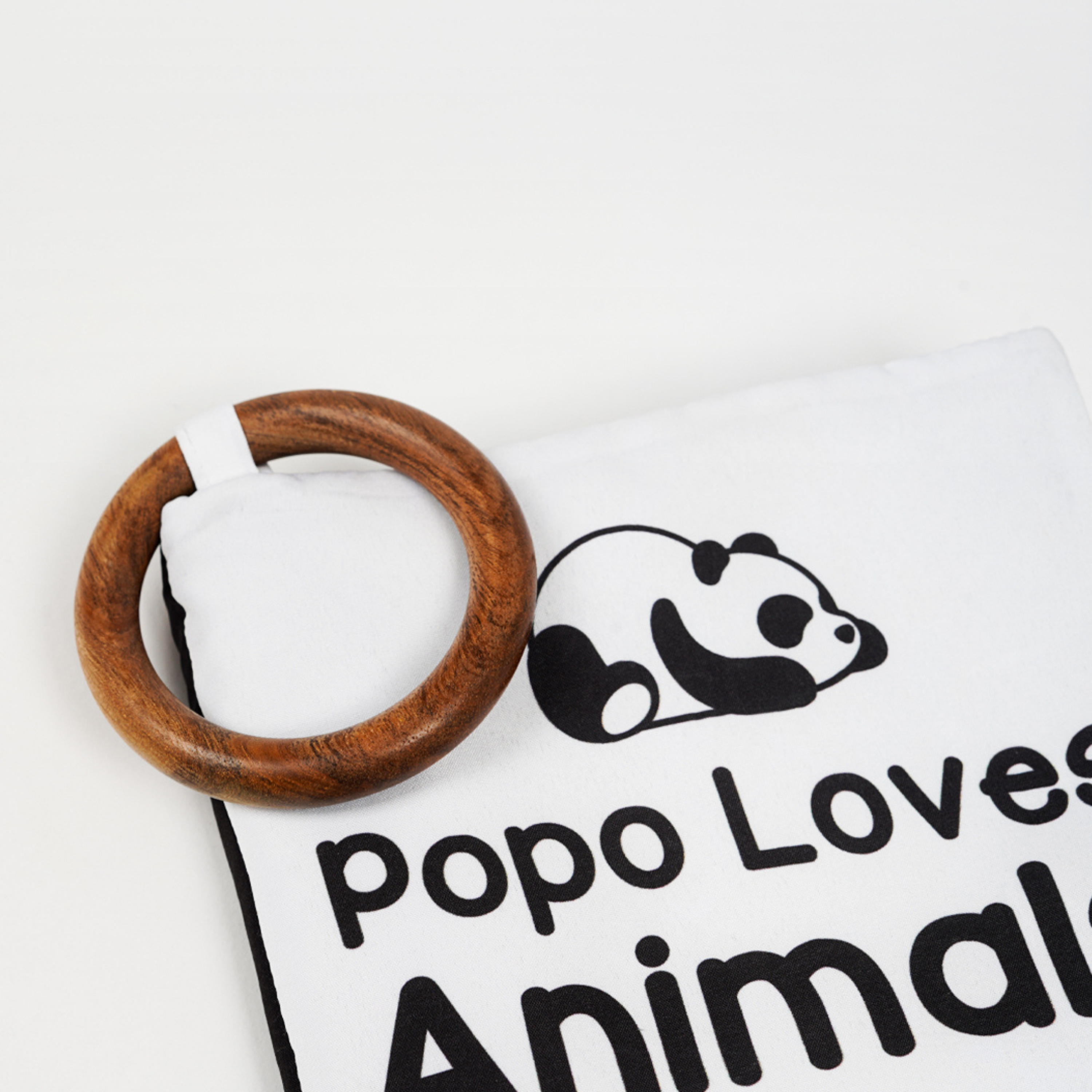 A closeup view of white and black high contrast book for baby along with a wooden teether for baby