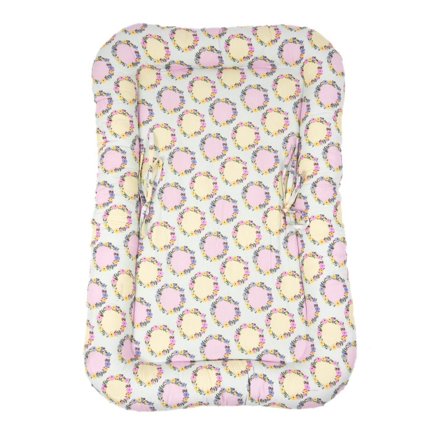A soft baby bed with a floral pattern featuring pastel circles and pink accents, designed for comfort and safety.