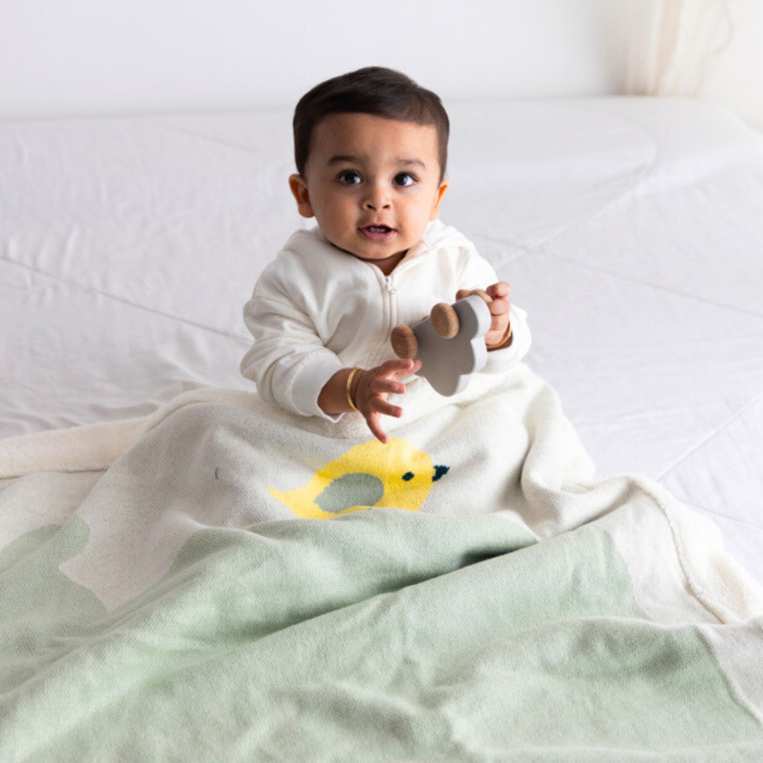 Baby wrapped in a soft green & white fleece blanket, showcasing cozy warmth and comfort.