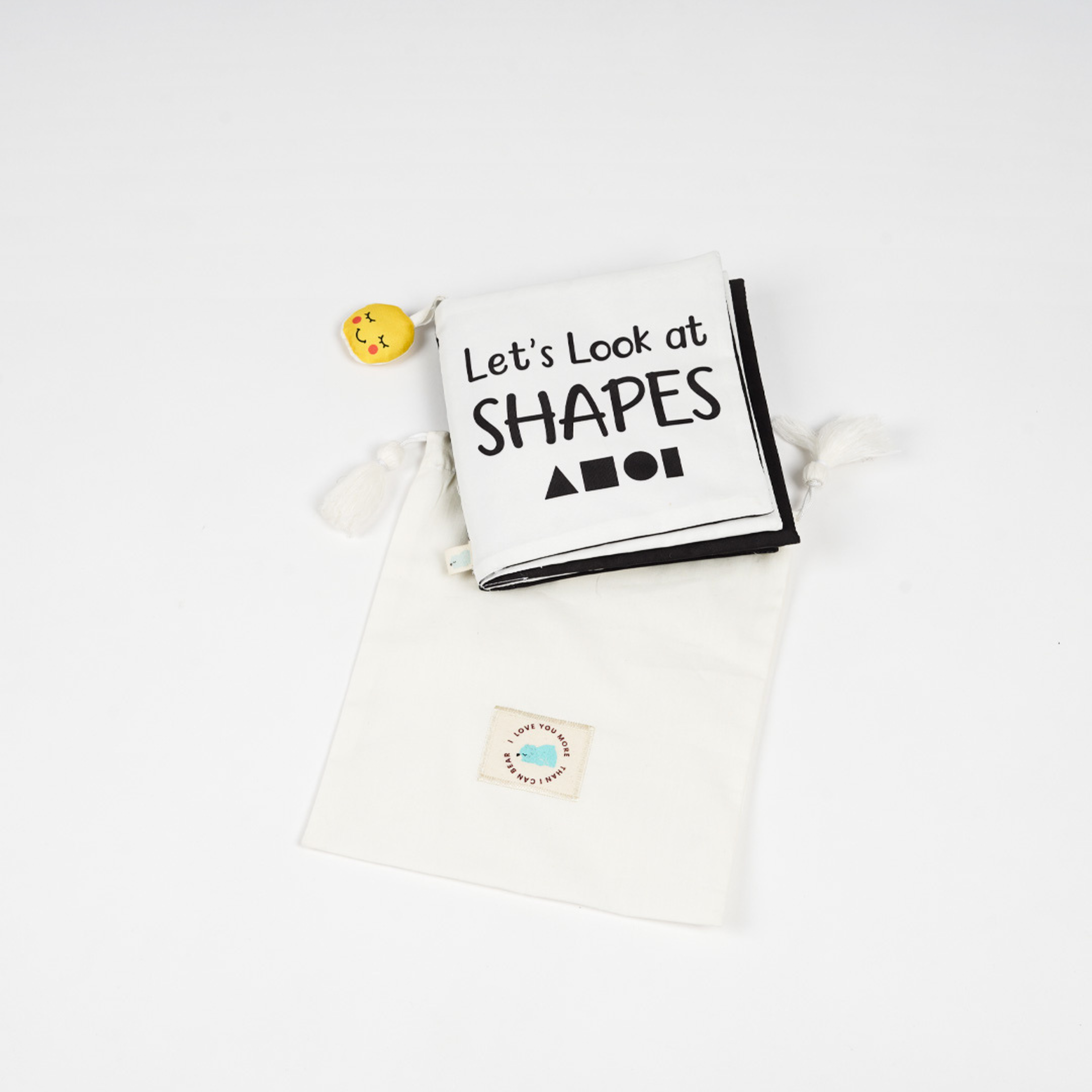A folded educational high contrast book fro baby titled "Let's Look at SHAPES," accompanied by a playful yellow toy, set on a white background.