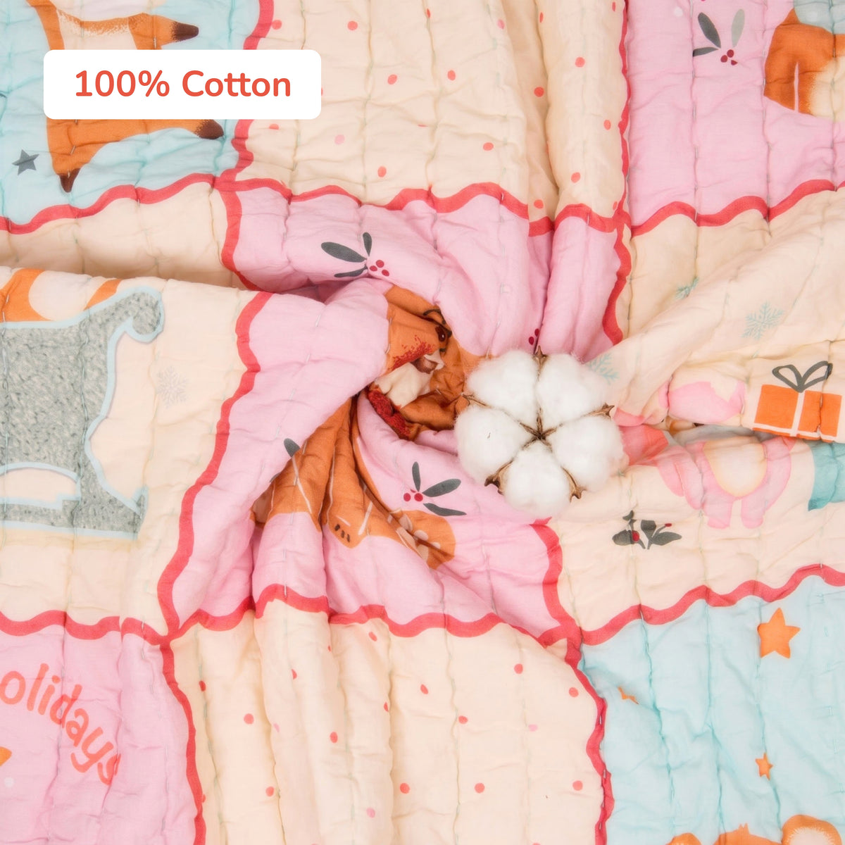 A close-up of a quilted cotton blanket with a holiday-themed print in pastel pink, beige, light blue, and orange. A white cotton boll is placed in the center, and a label reads '100% Cotton'.