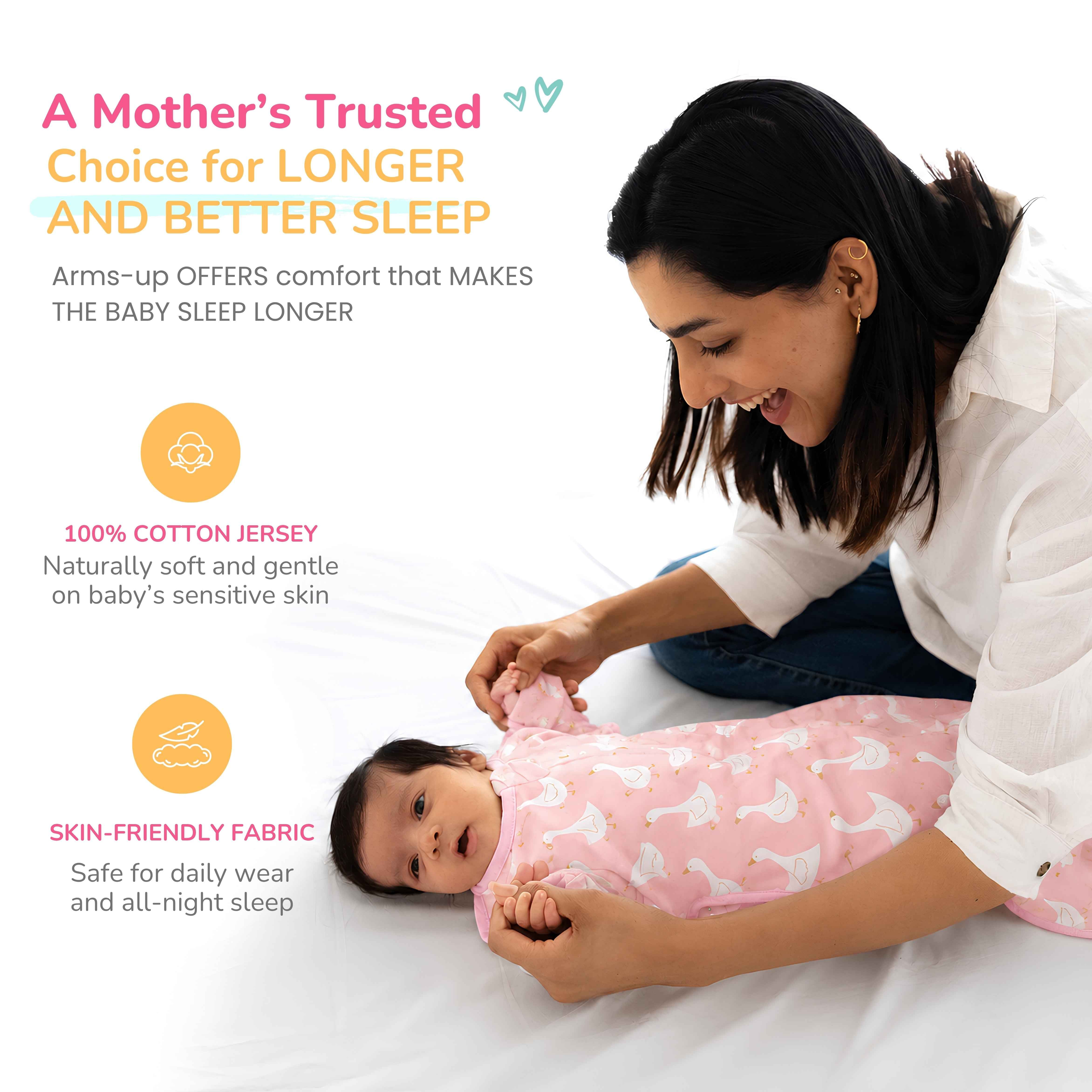 A woman sitting on a white bed holding baby hand wrapped in a a pink arms-up cotton swaddle with a white duck pattern on a baby. The image includes marketing text highlighting the product's comfort, cotton jersey material, and skin-friendly fabric.