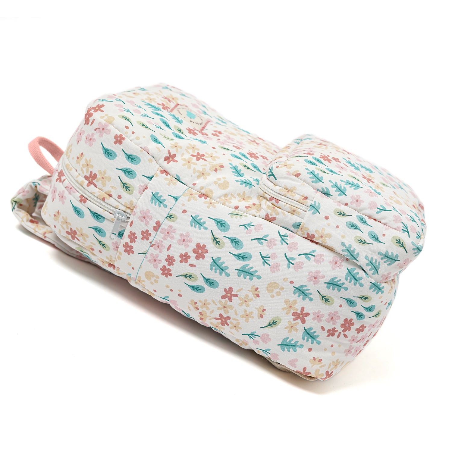 A white backpack with a pattern of flowers and leaves in shades of pink, green, and blue