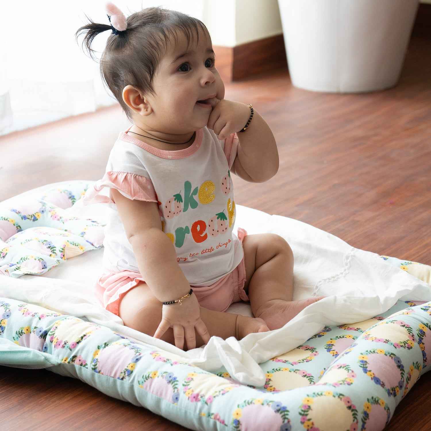 A baby sitting in a ballerina print gadda set with Mosquito Net