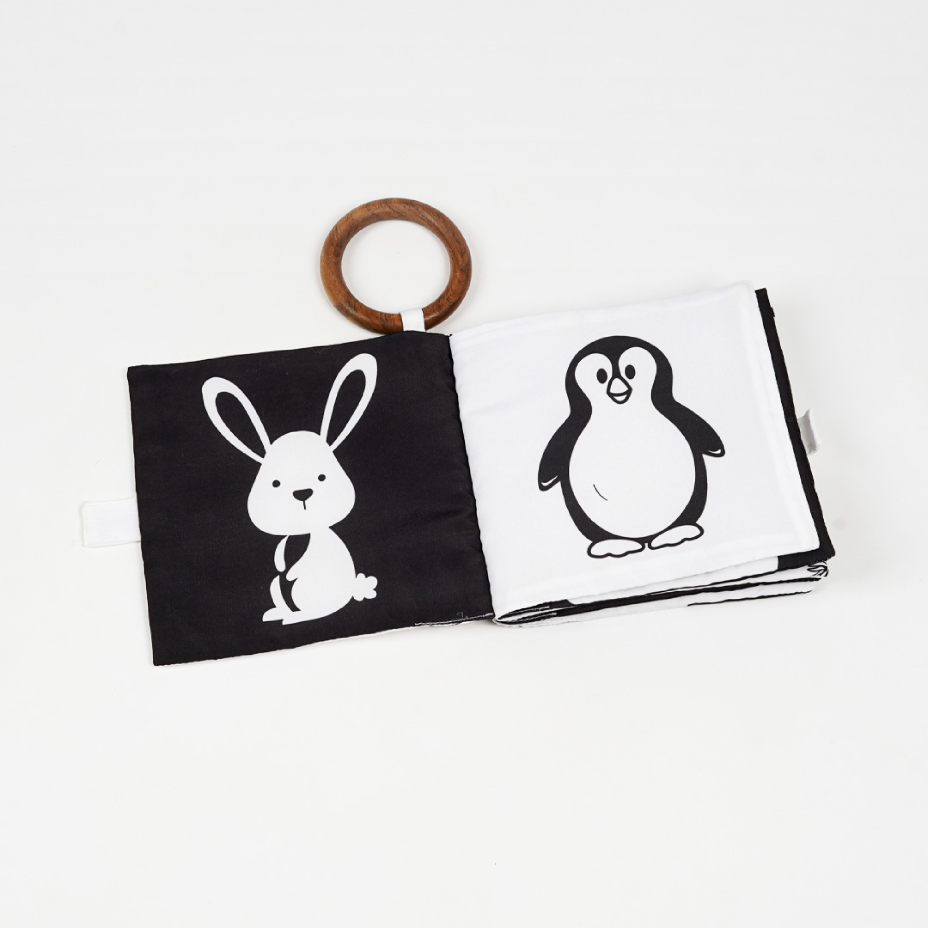 Black and white cloth fabric high contrast book for baby featuring a bunny and a penguin, with a wooden ring attachment.