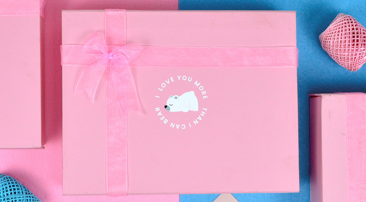 A pink gift box with a ribbon, featuring a polar bear illustration and the text "I LOVE YOU MORE THAN I CAN BEAR," on a colorful background.