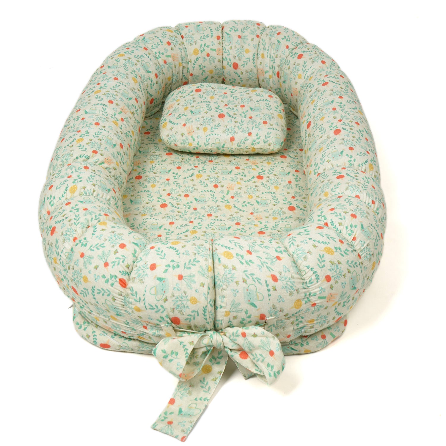 A cozy baby nest bed with a floral pattern, featuring a removable cushion and decorative bow on one side.