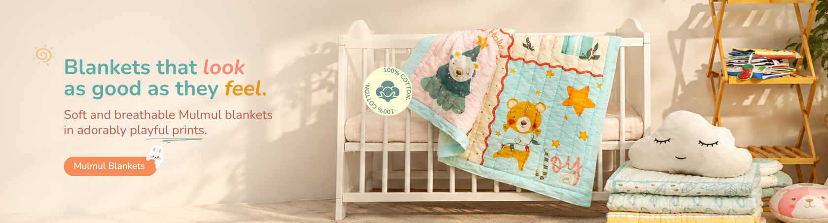 A baby crib scene showing a colorful quilted blanket with cartoon animal prints, styled in a nursery setting with a white cloud pillow, folded blankets, and a wooden shelf in the background.