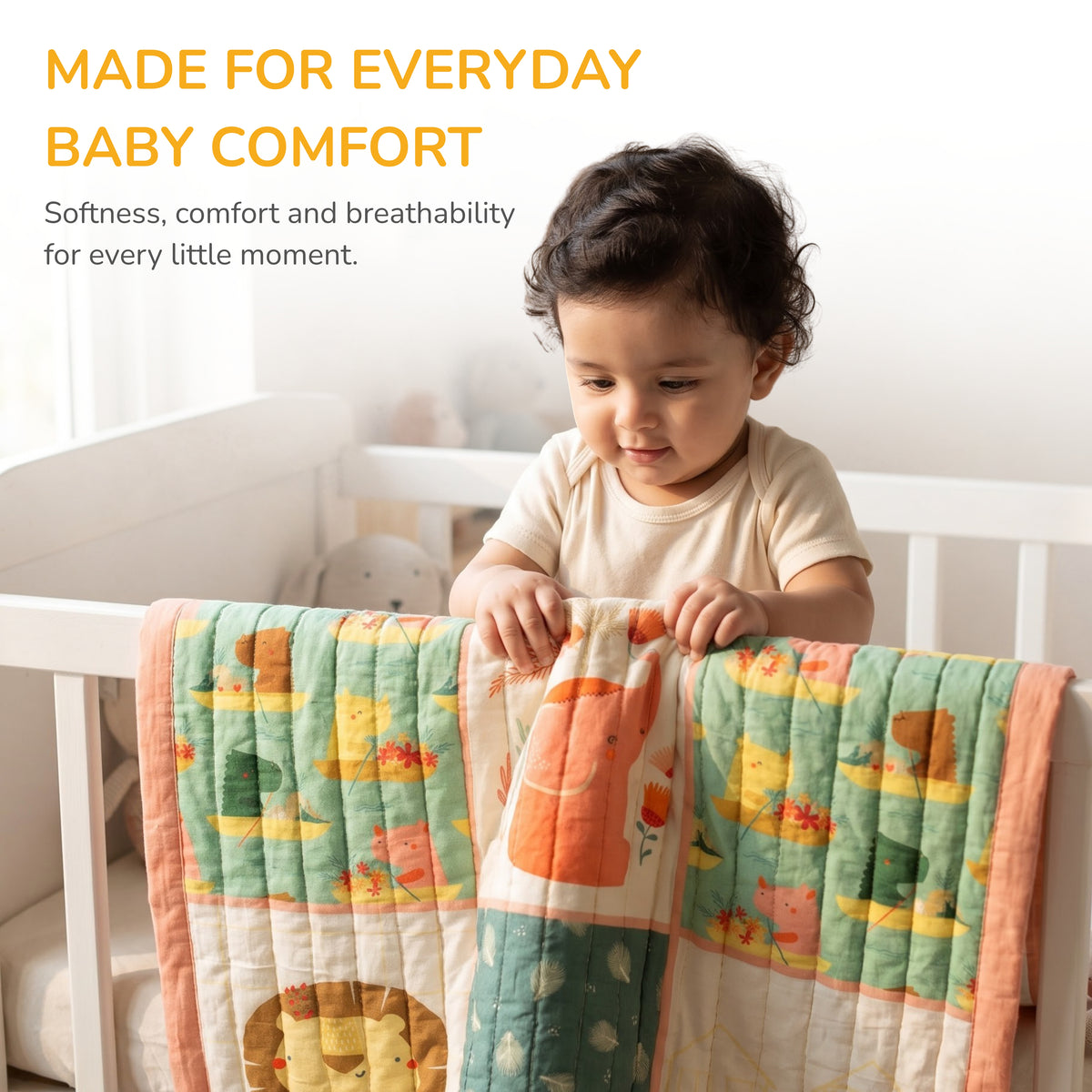 A baby in a cream t-shirt sits in a white crib holding a colorful patchwork quilt with cartoon animal prints. Text at the top reads 'MADE FOR EVERYDAY BABY COMFORT' with smaller descriptive copy below.