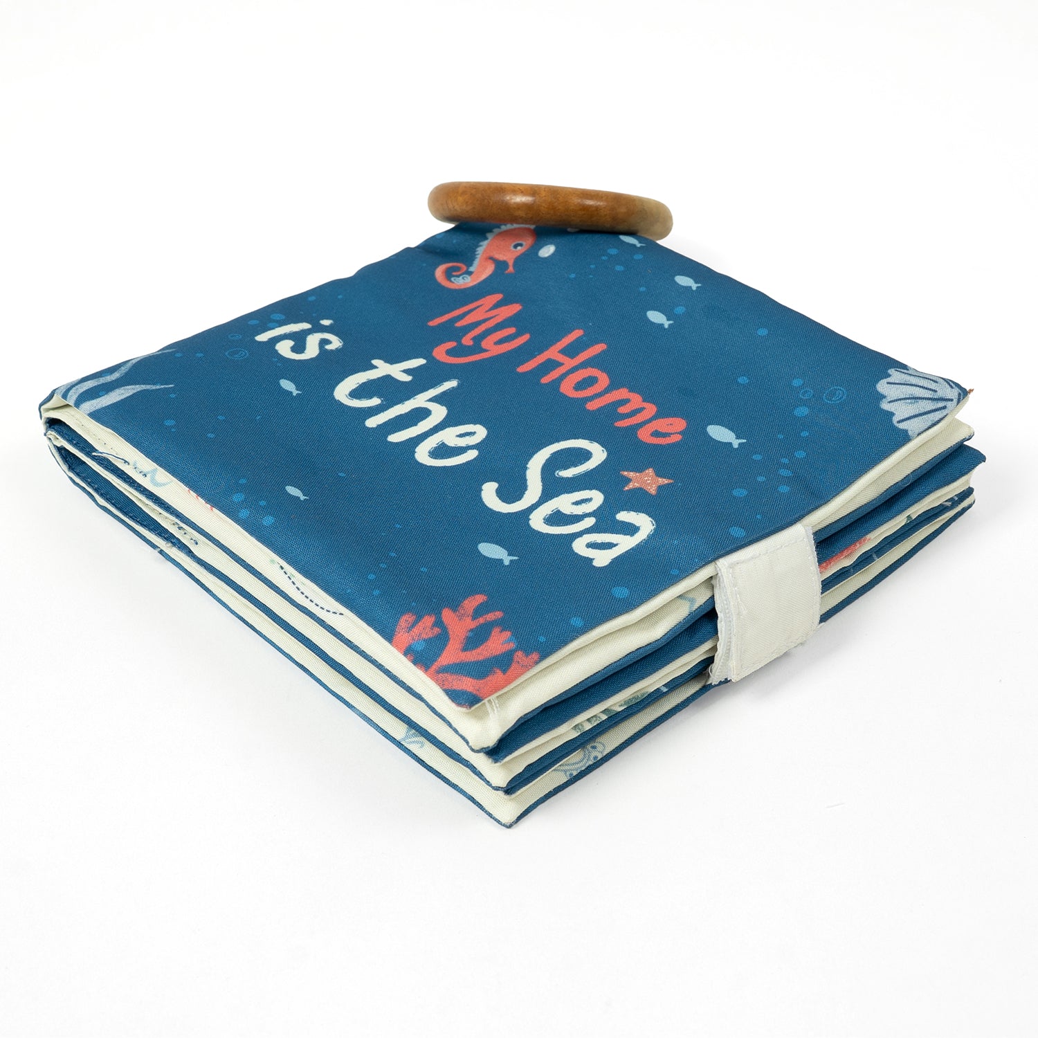 A folded fabric book with a blue cover featuring the text "My Home is the Sea" and colorful sea-themed illustrations.