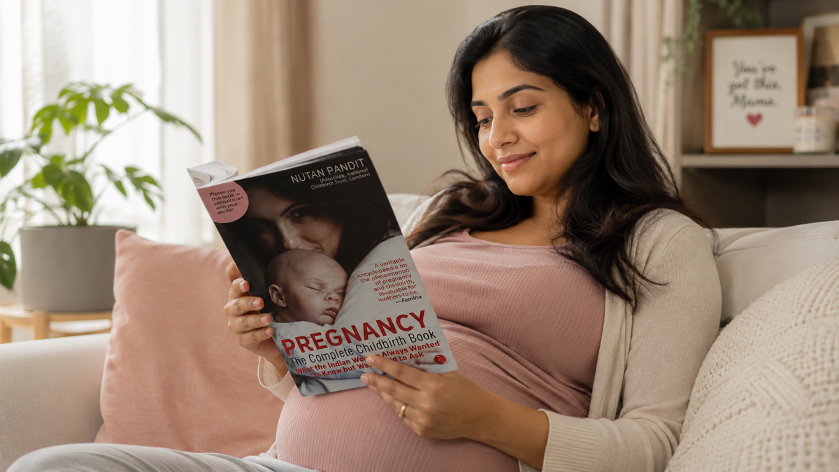 A pregnant woman sitting on a beige sofa in a cozy living room, holding and reading a book titled 'Pregnancy: The Complete Mother-in-Law Book'.
