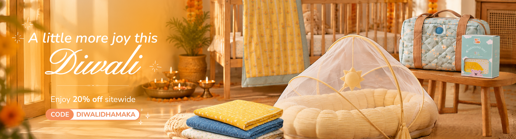 A cozy nursery scene with baby bedding and accessories arranged on a wooden bench and floor. A white mesh baby tent with a yellow star is in the foreground, with folded yellow and blue blankets beside it.