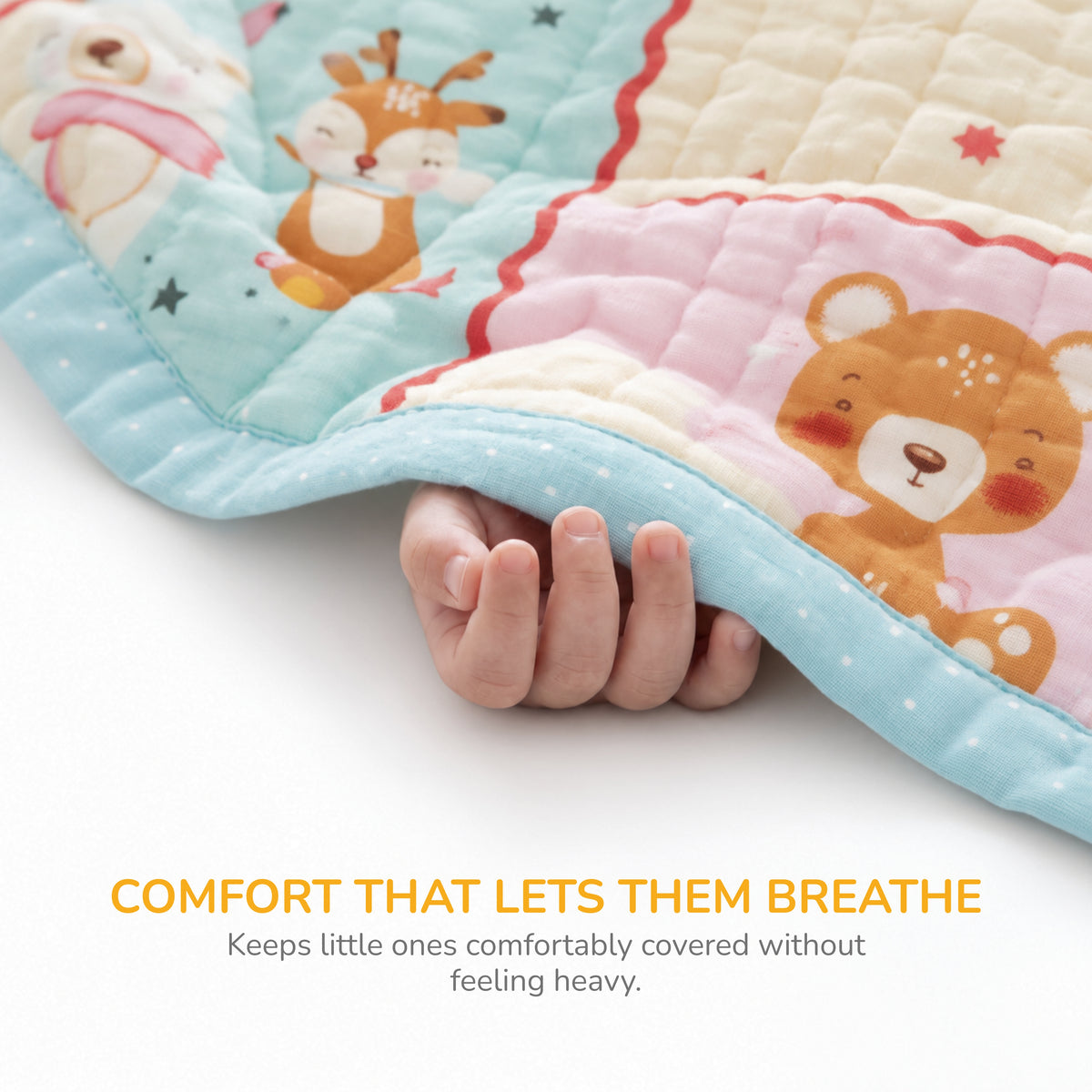 A close-up of a quilted baby blanket with cartoon animal prints, being held down by a baby's hand to show its softness. The blanket features a light blue border, a cream section with a deer, and a pink section with a bear.